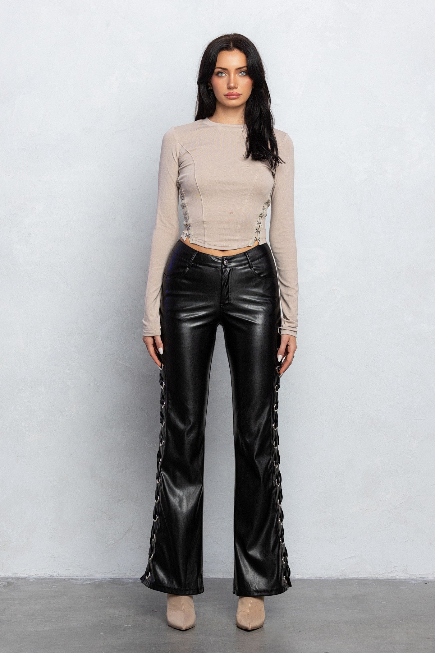 Black laced up boot cut pleather pants with grommet details and pockets, designed for an edgy yet stylish outfit.