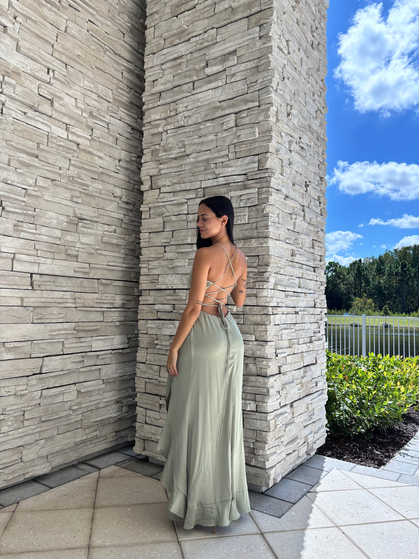 Sage satin maxi dress with a corset bodice, ruffled surplice skirt, and open back tie details, perfect for formal spring occasions