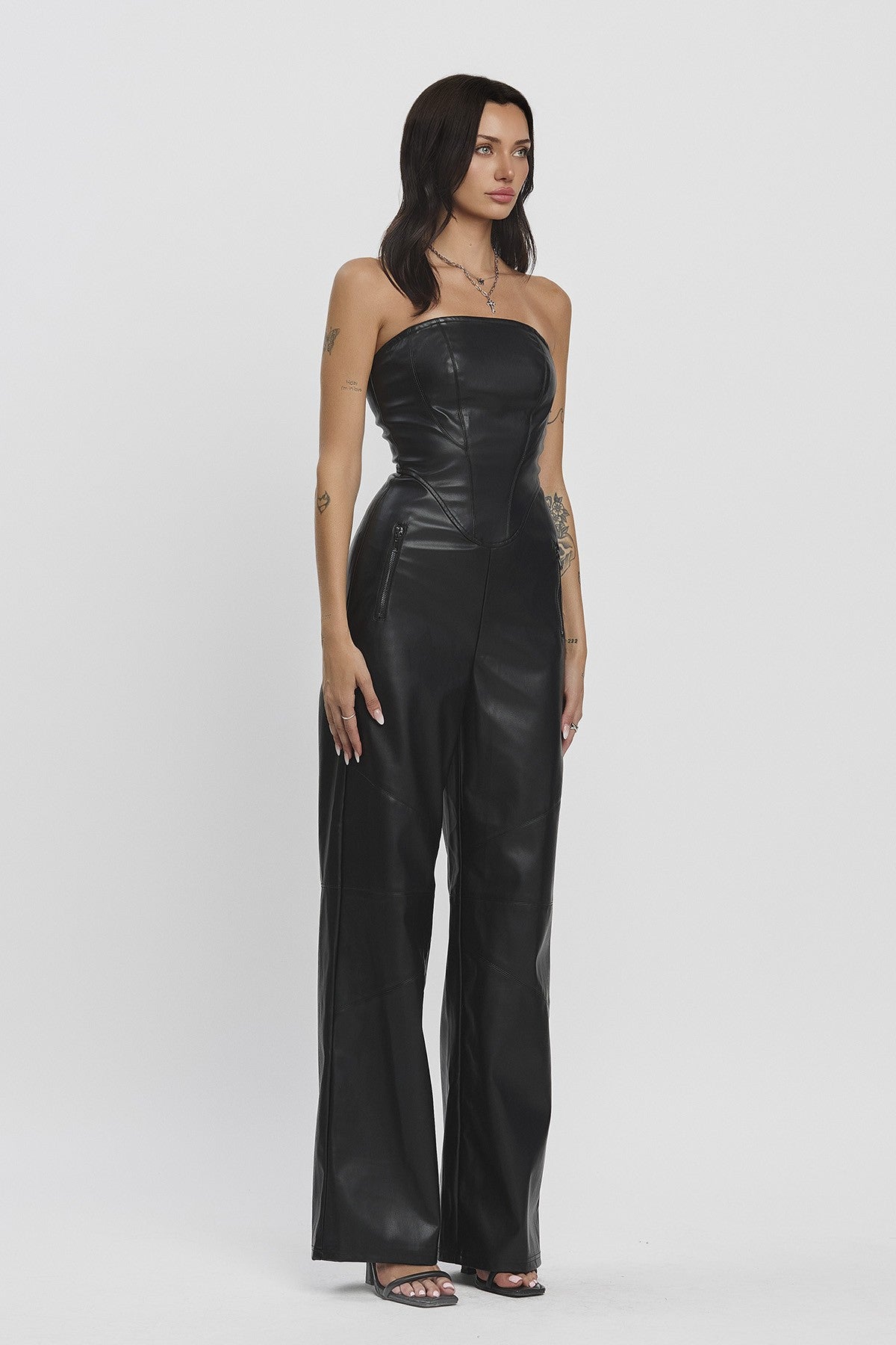 Starlit Muse Jumpsuit featuring a strapless fitted top, zipper pockets, and wide-legged pants in black faux leather.