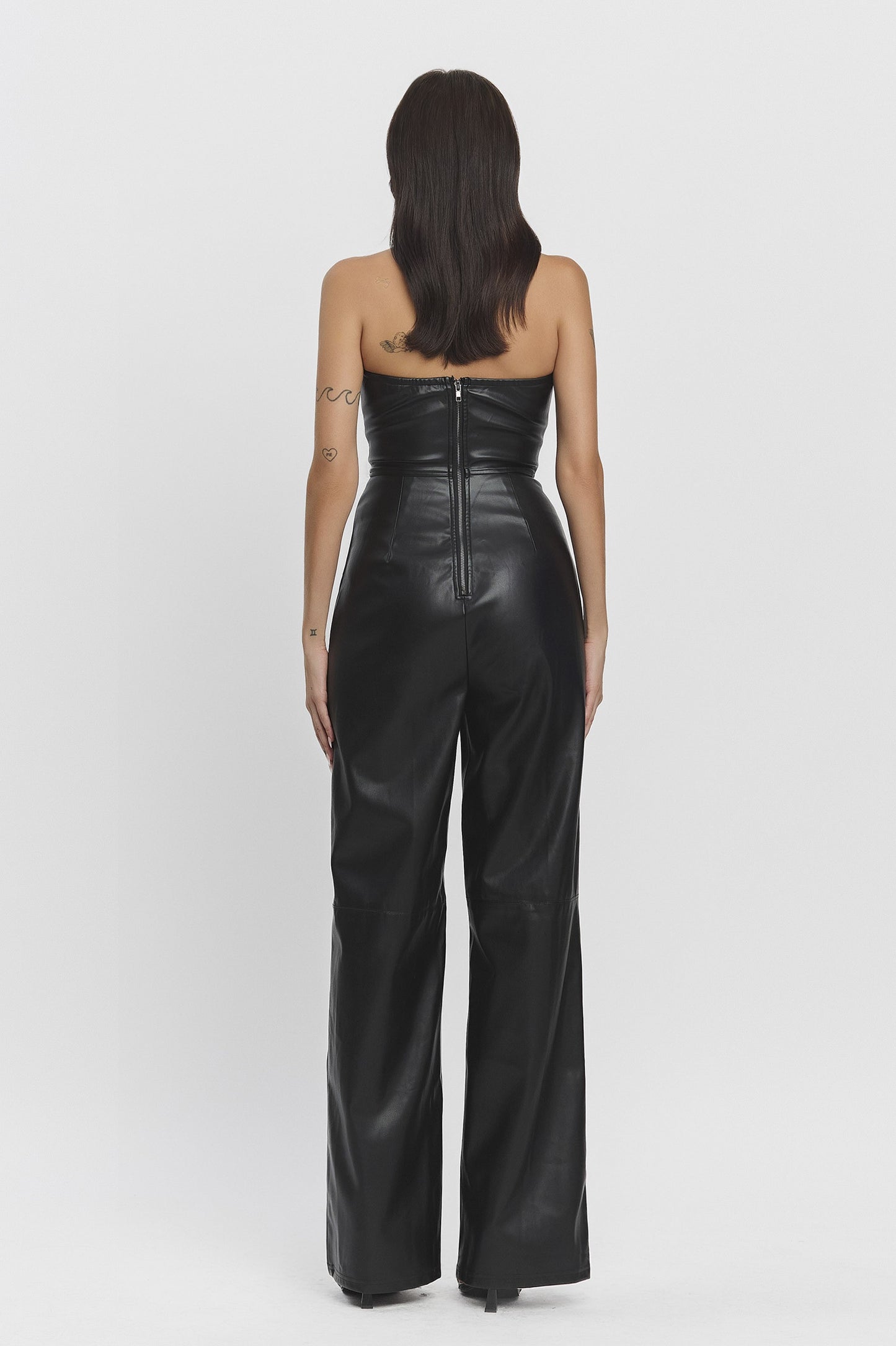 Starlit Muse Jumpsuit featuring a strapless fitted top, zipper pockets, and wide-legged pants in black faux leather.