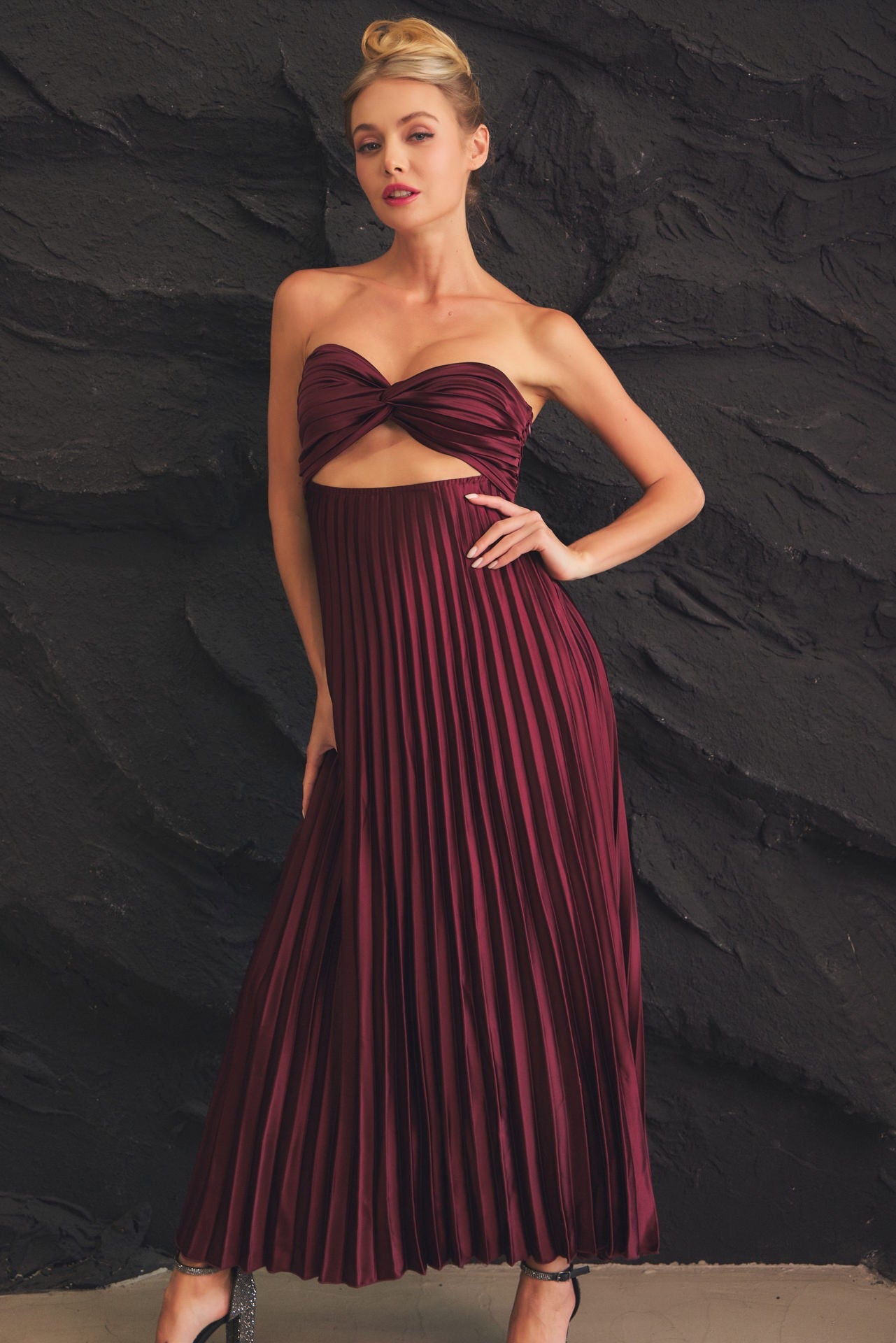 Burgundy strapless dress featuring a twist-front bodice and flowy pleated skirt, perfect for formal events and elegant celebrations.