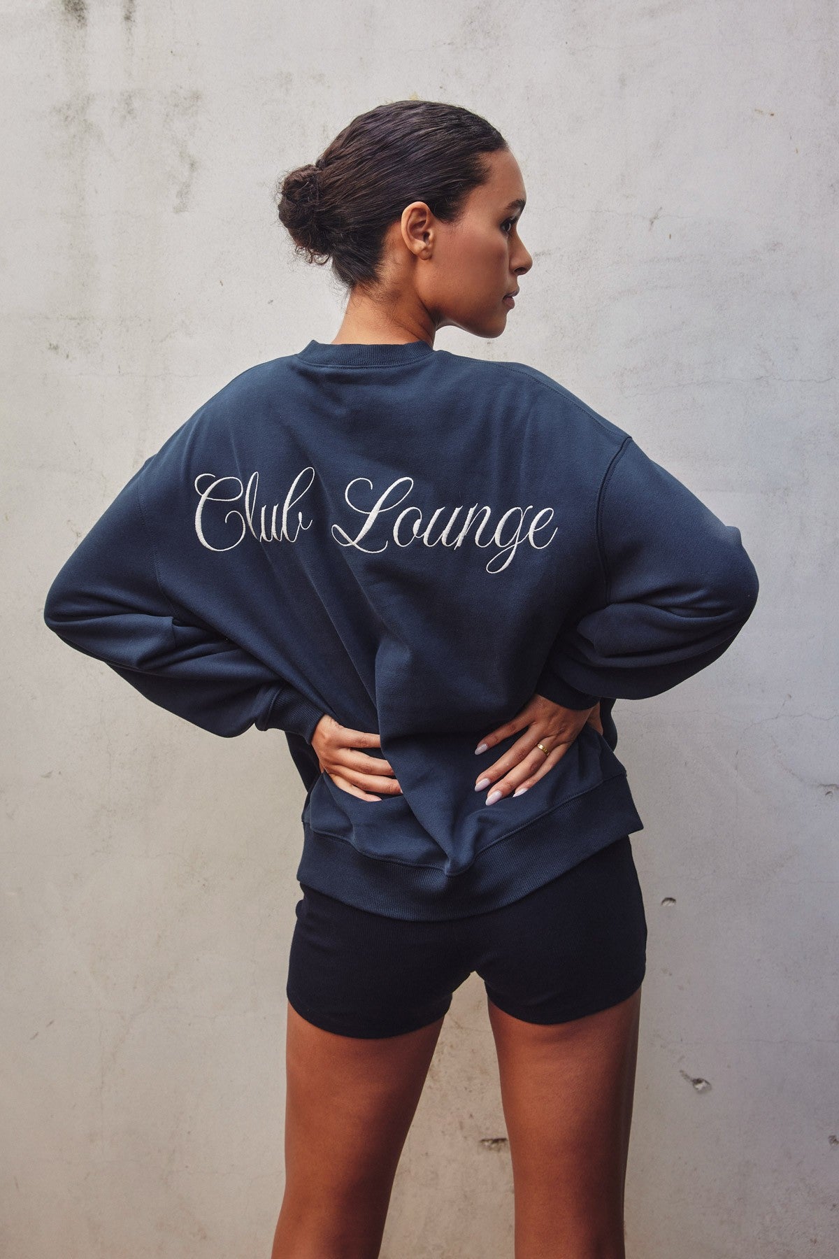 Model showcasing an oversized travel-inspired sweatshirt with embroidery in Brown and Navy colors, ideal for casual wear.