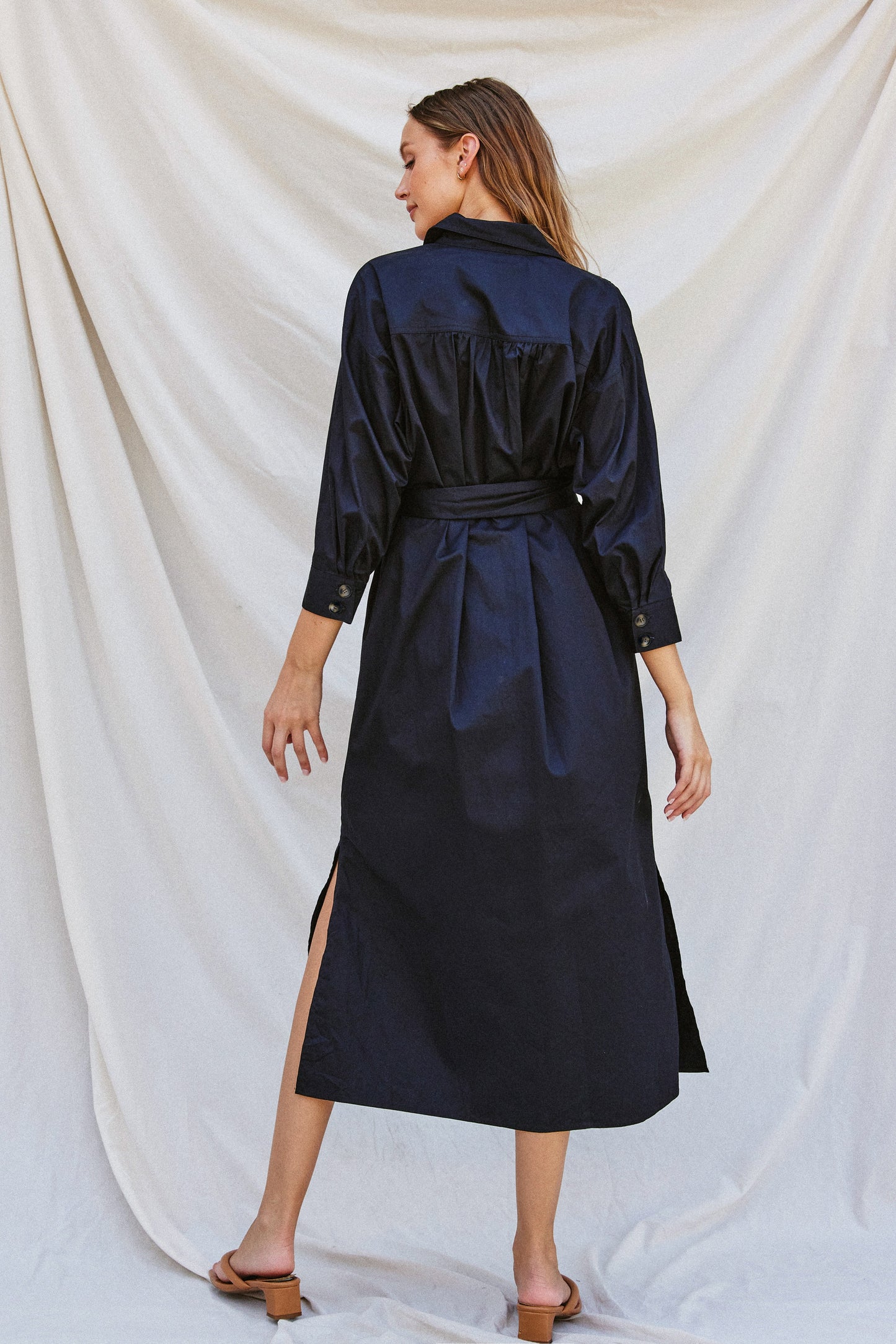 Navy poplin midi dress with a collared neckline, tortoise buckled belt, long sleeves, and side pockets, styled for work or fall gatherings.