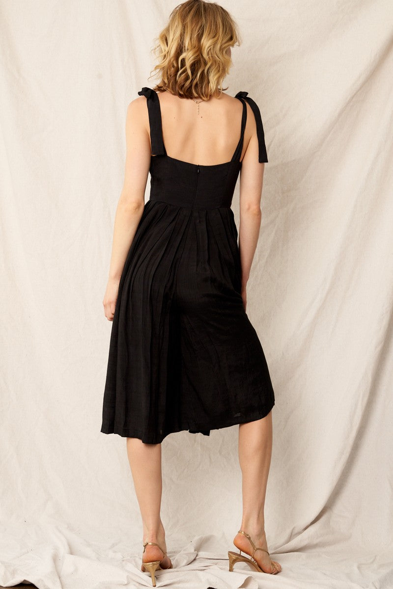 Elegant black jumpsuit with shoulder tie straps, pleated wide-leg pants, and hidden back zipper closure. Perfect for holiday outfits and formal occasions