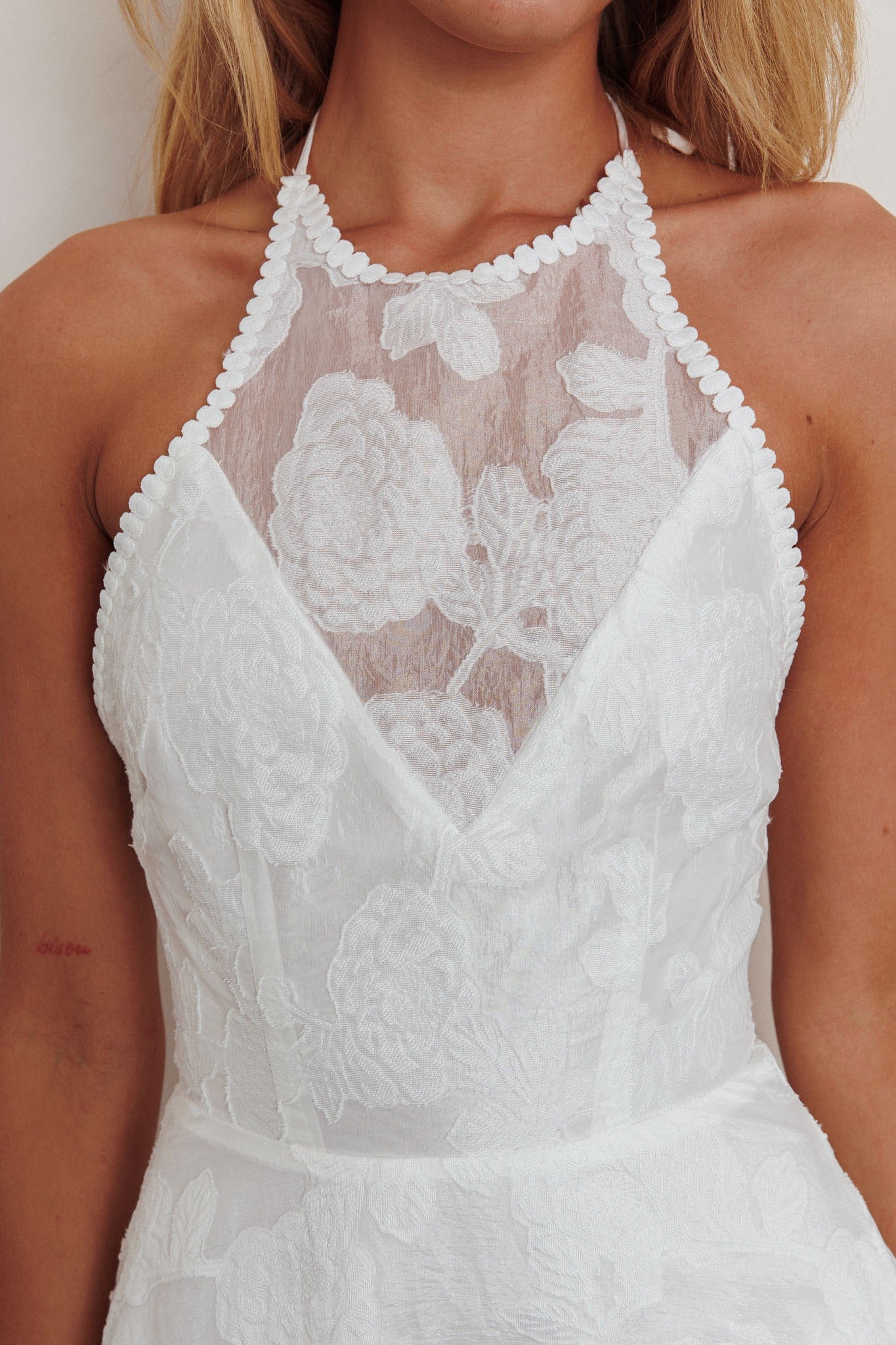 The Petal Whisper Bridal Dress, a strapless halterneck dress with floral lace details and an open back, in elegant white.