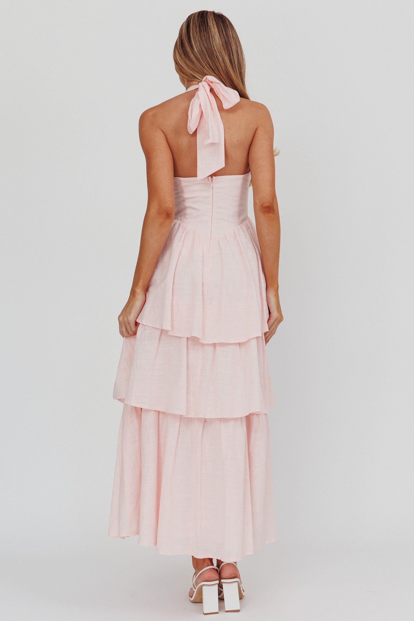 Pink Whisper Halter neck Corset Dress in pastel pink with a tiered skirt, halter top, and back zipper.