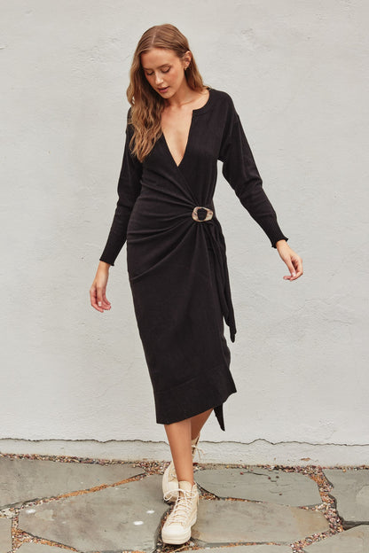 Black pull-over knit midi dress with a wrapping top layer, buckle fastening, and snap button neckline, perfect for winter casual wear and brunch.