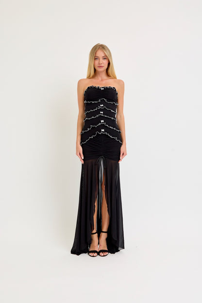 Strapless black maxi dress with ruffle and bow details, featuring a bodycon fit and a sheer mesh skirt, ideal for birthdays and evening events.