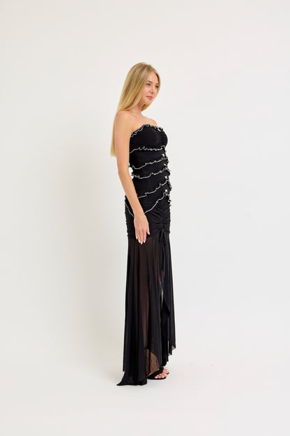 Strapless black maxi dress with ruffle and bow details, featuring a bodycon fit and a sheer mesh skirt, ideal for birthdays and evening events.