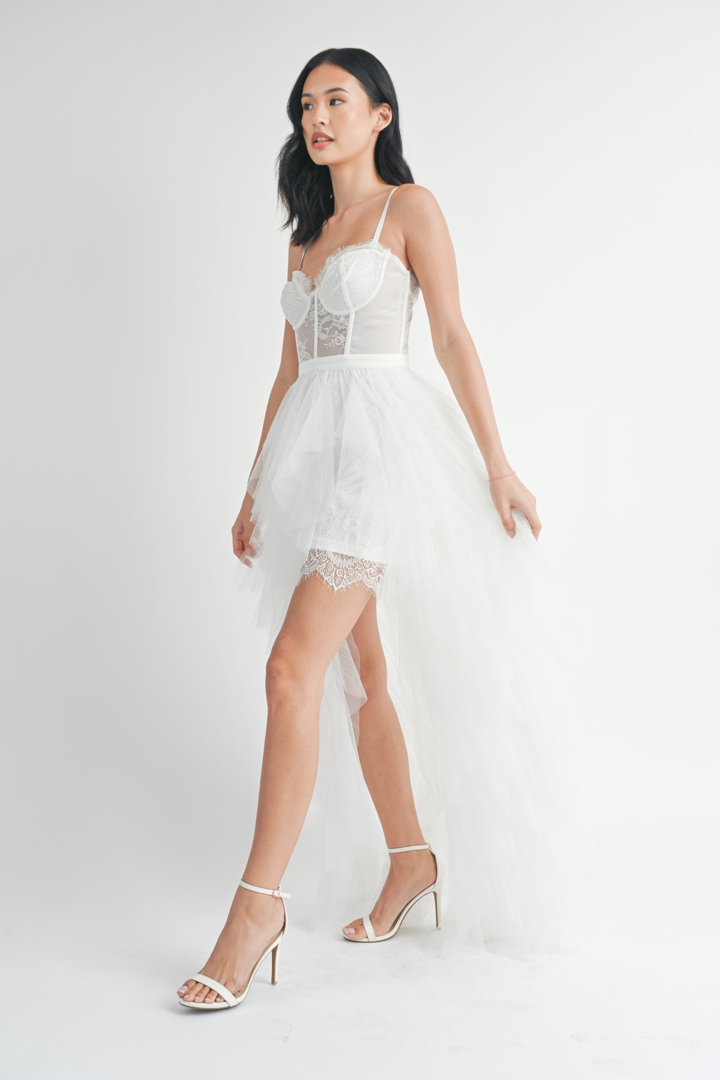 White strapless tulle maxi dress with a structured lace bodice, side slit, and ruffled mesh outer layer.