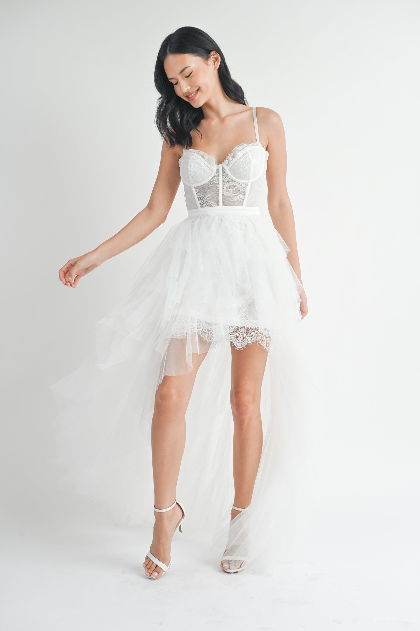 White strapless tulle maxi dress with a structured lace bodice, side slit, and ruffled mesh outer layer.