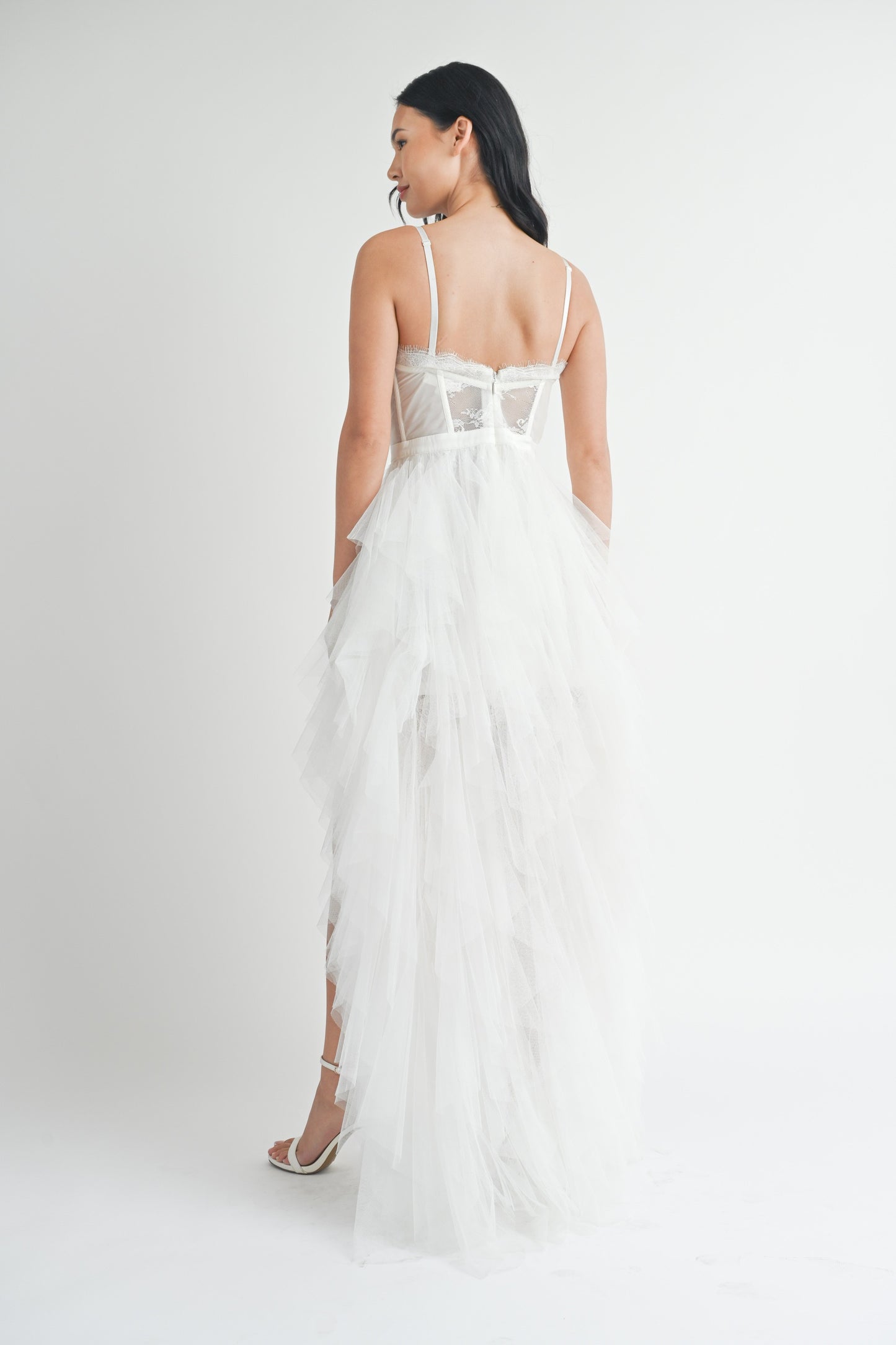 White strapless tulle maxi dress with a structured lace bodice, side slit, and ruffled mesh outer layer.